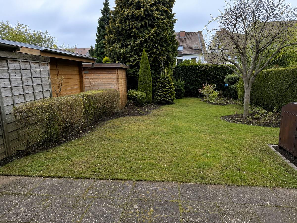 Derselbe Garten nach der Pflege: gemähter Rasen, geschnittene Hecke, saubere Beetkanten.