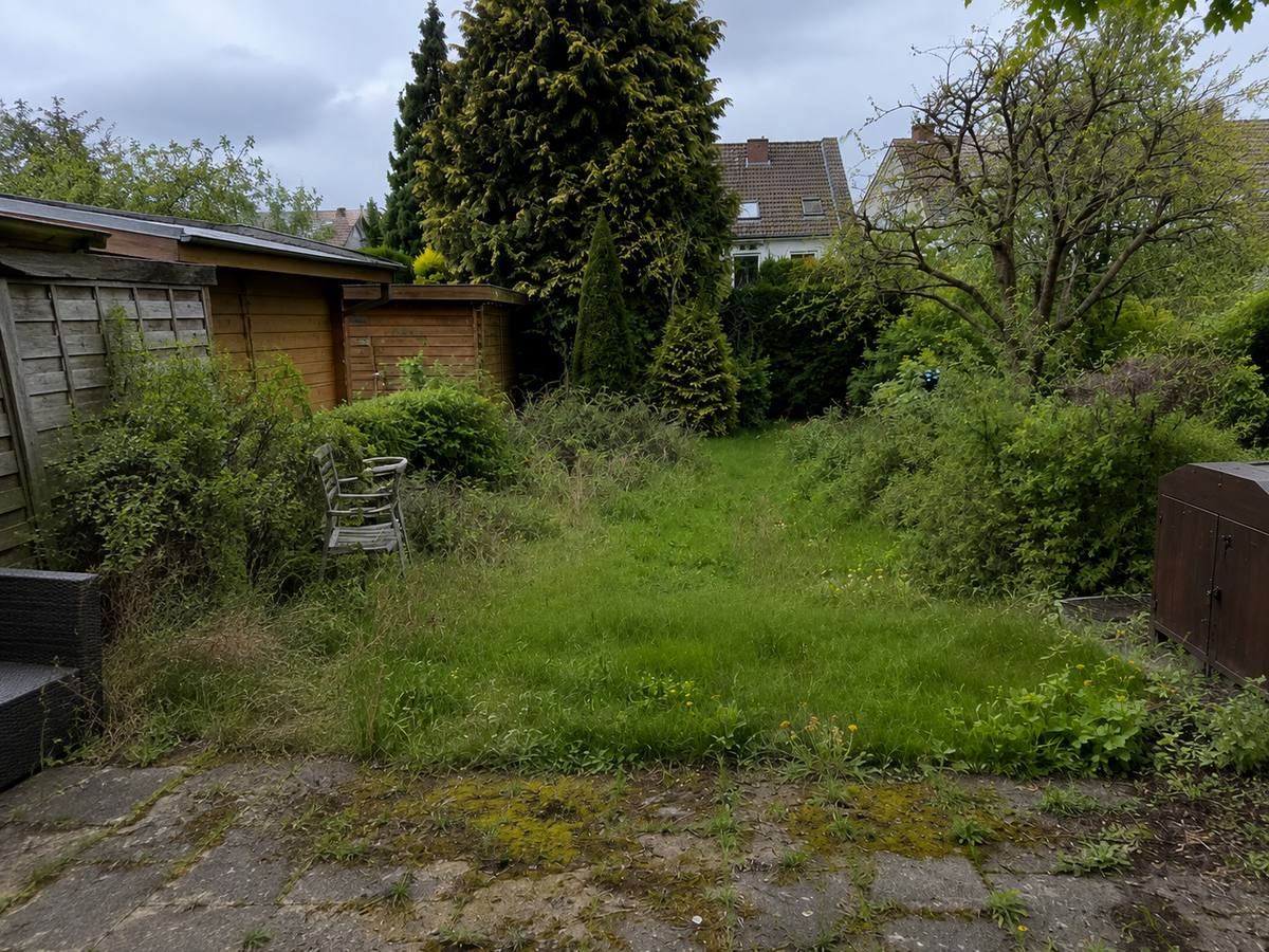 Garten vor der Pflege: hohes Gras, wucherndes Gebüsch, überwachsene Beete.